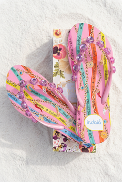 Sandalias con caja floral sobre arena blanca