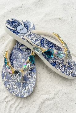 Sandalias cruzadas sobre arena blanca